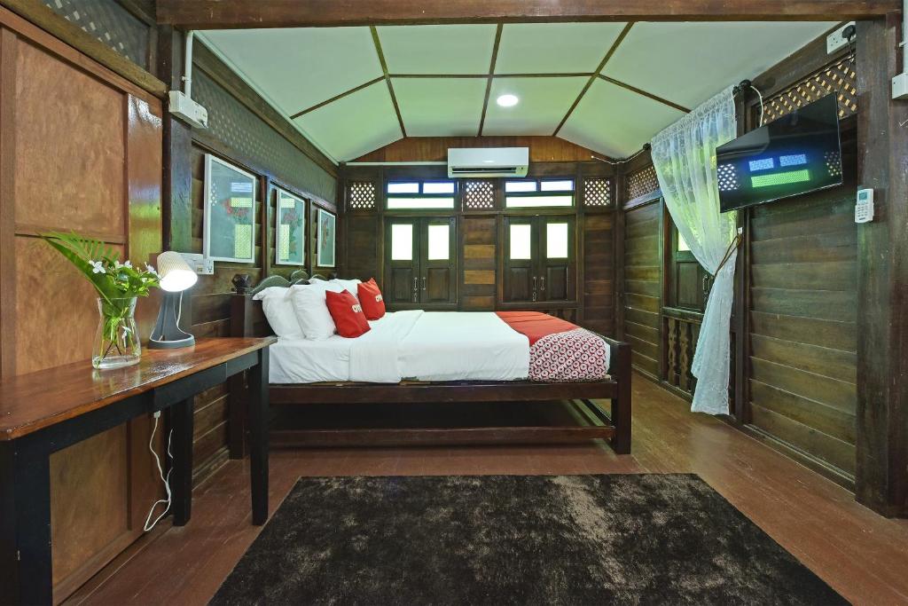 珍南海滩Collection O 90622 Sehijau Cenang的一间卧室配有一张床、一张书桌和一台电视