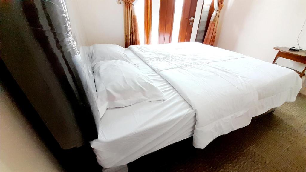 美娜多RedDoorz Syariah @ Jalan Pingkan Matindas Manado的一张铺有白色床单的床和木制床头板