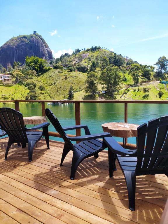 瓜塔佩Ecolodge Bahia del Peñón的甲板上配有三把椅子和一张桌子,享有水景