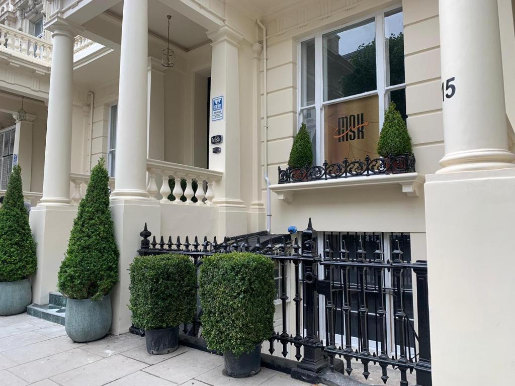 伦敦MSK Elite的白色的房子,有黑色的围栏和灌木
