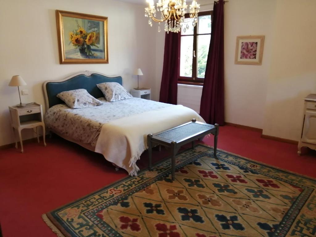 科尔鲁瓦拉罗克Le Breval的一间卧室配有一张带地毯和吊灯的床。
