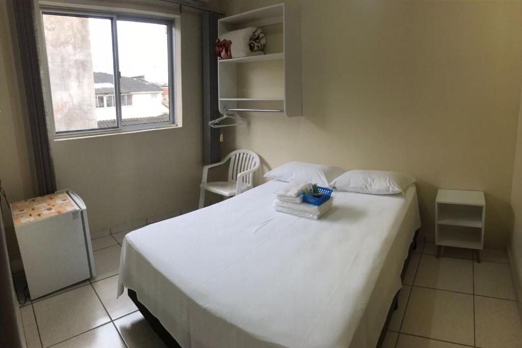 瓜拉图巴Stela Maris的卧室配有白色的床和窗户。