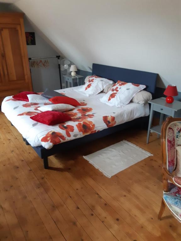 Saint-UrbainLes Coquelicots的一间卧室配有一张带红色枕头的床