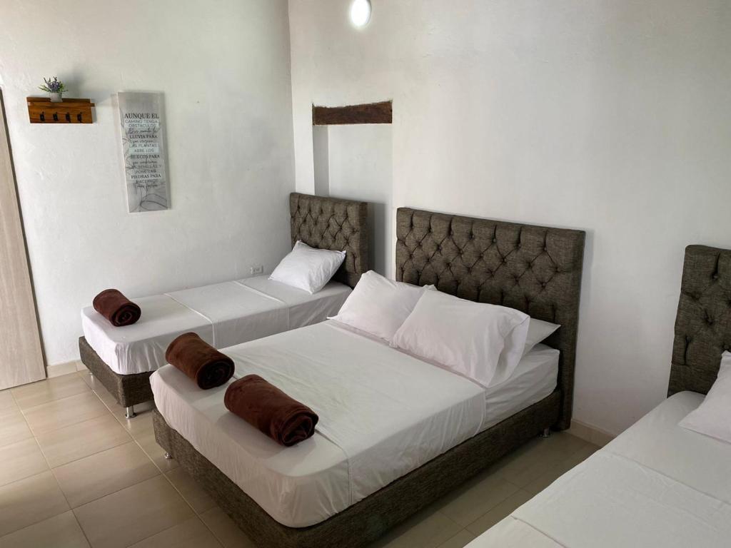 蒙波斯HOTEL PLAZA BOLIVAR MOMPOX ubicado en el centro histórico con parqueadero interno的一间卧室配有两张带棕色枕头的床