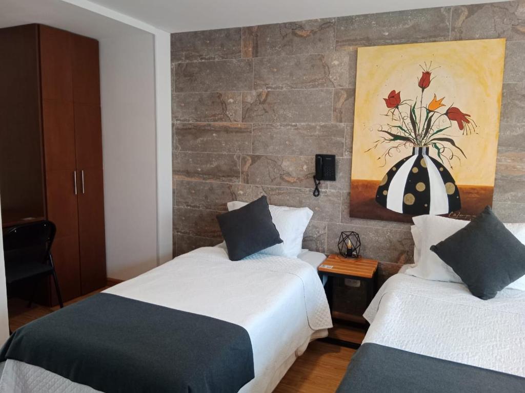 通哈Hotel Posada de Santa Elena的一间卧室设有两张床,墙上挂着一幅画