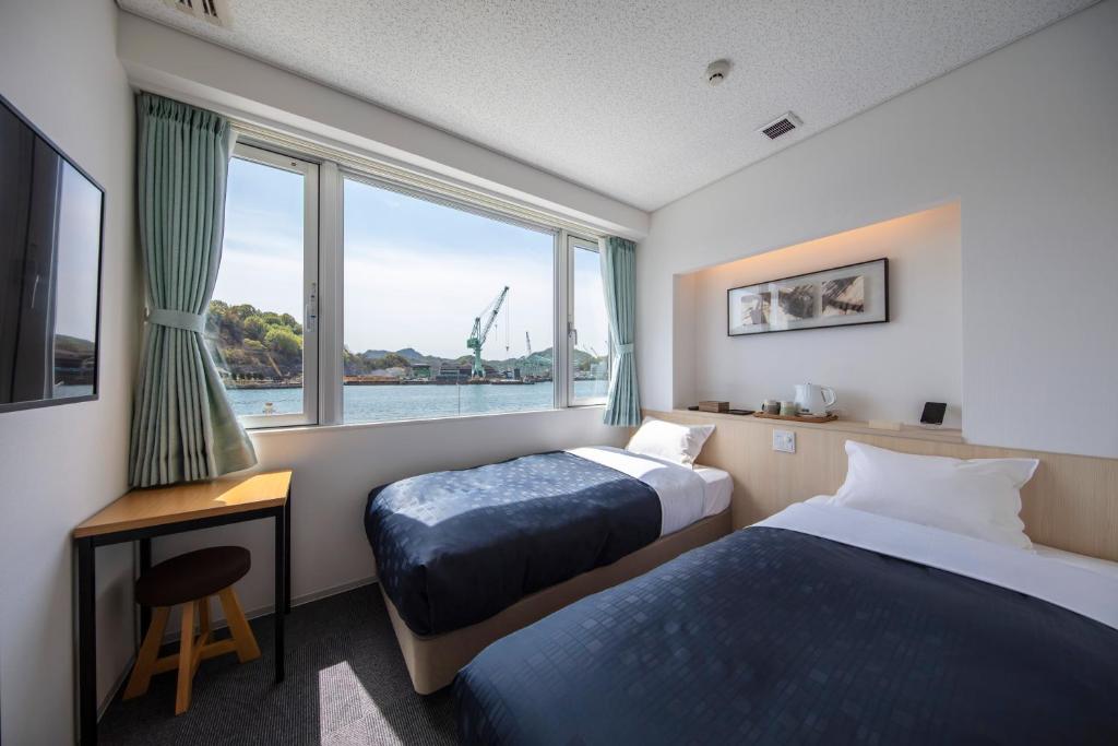 尾道市urashima INN - GANGI -的酒店客房设有两张床和窗户。