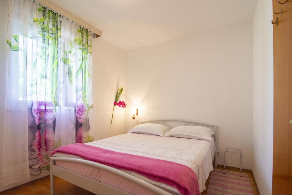 奥库格哥恩基Apartments by the sea Okrug Donji, Ciovo - 15655的一间卧室配有一张带粉色毯子的床