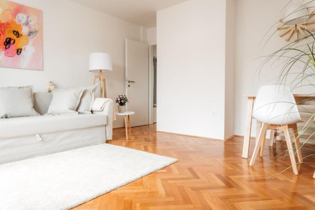 卢布尔雅那White Apartment的客厅设有白色沙发和木地板