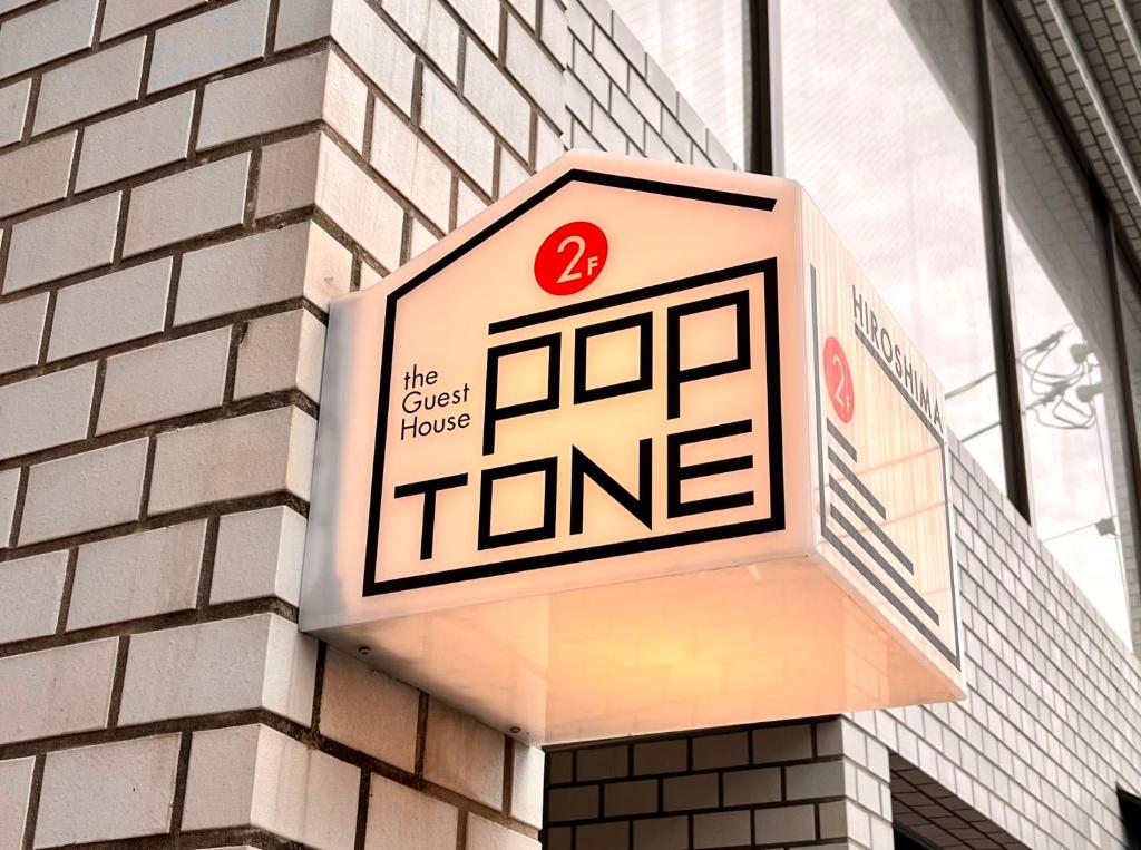 广岛Guesthouse POPTONE的大楼上读取旅馆音的标牌