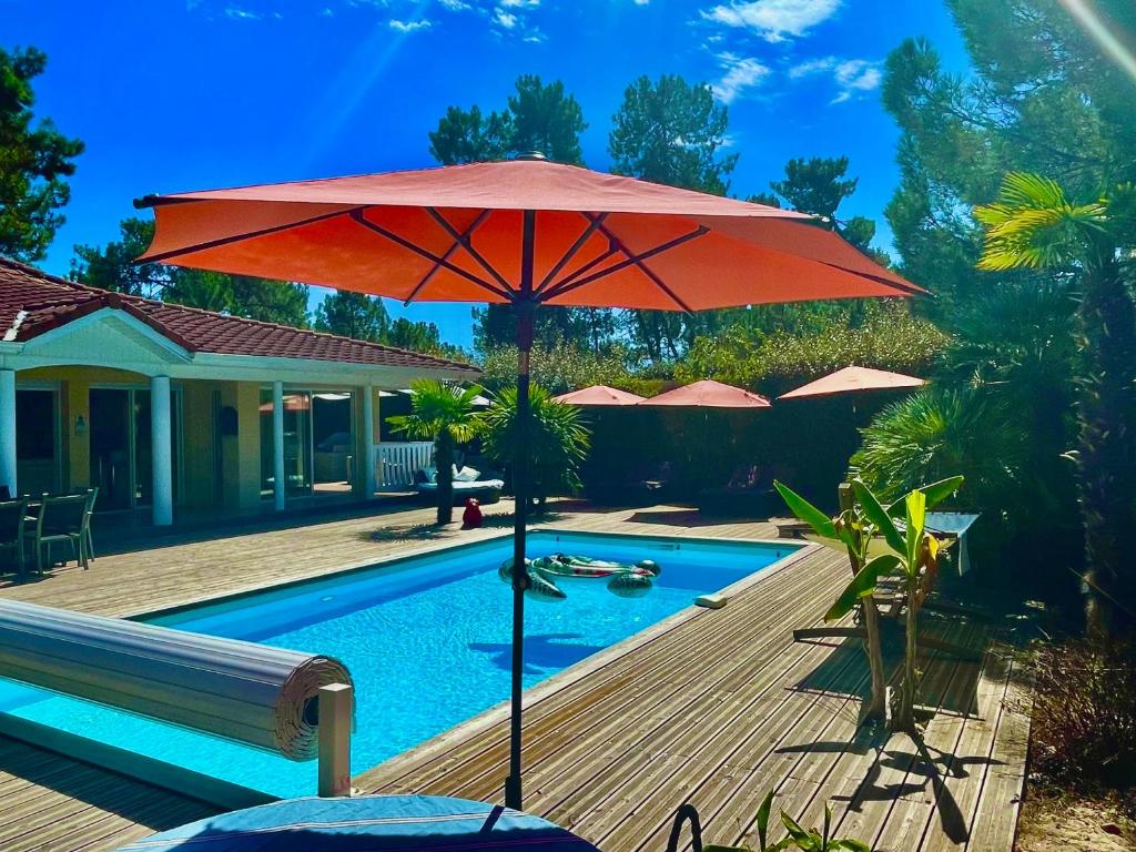 拉卡诺Villa NIKKITA的游泳池旁的一把红色大遮阳伞
