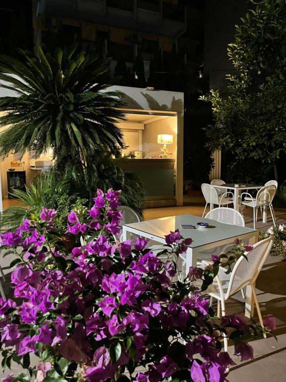 巴列塔Liddo Boutique hotel的庭院里种有紫色花卉,配有桌椅