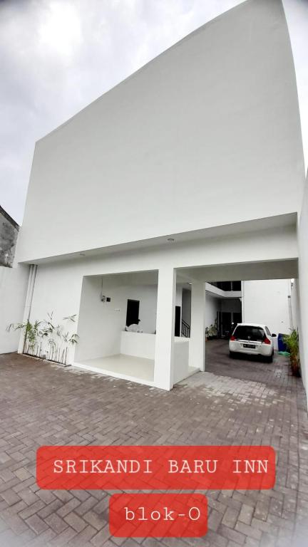 班图尔Srikandi Baru Inn Blok O的停车场内有停车位的白色建筑