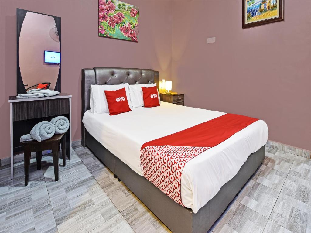 珍南海滩OYO Home 90348 Inspire Rooms的一间卧室配有一张带红色枕头和镜子的床