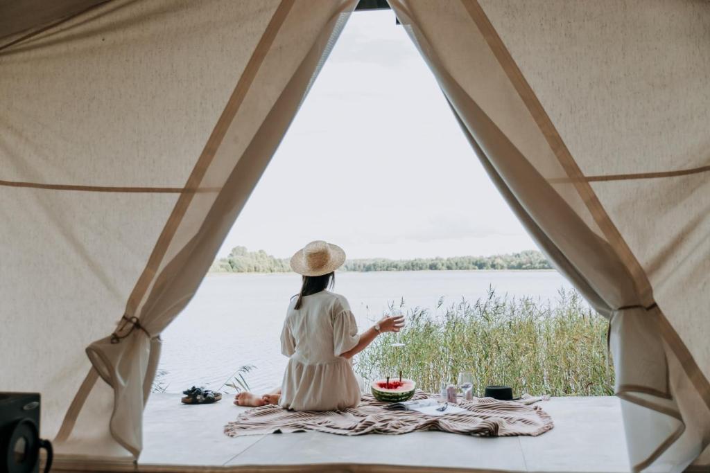 科沃拉Tykkimäki Resort的坐在帐篷里看着水面的女人