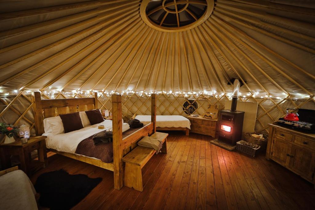 CauldonSecret Cloud House Holidays Luxury Yurts with Hot Tubs的蒙古包内一间卧室,配有一张床和炉灶