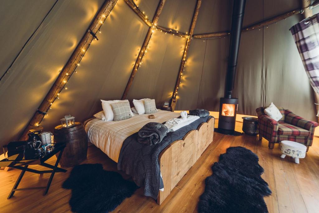 SheenScaldersitch Farm Boutique Camping Tipi with private wood fired hot tub的一个带床的卧室,位于带灯的帐篷内