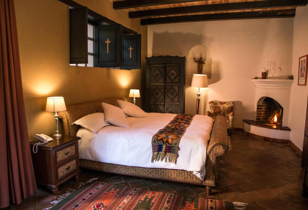 圣克里斯托瓦尔-德拉斯卡萨斯番石榴精品酒店的一间卧室设有一张大床和一个壁炉