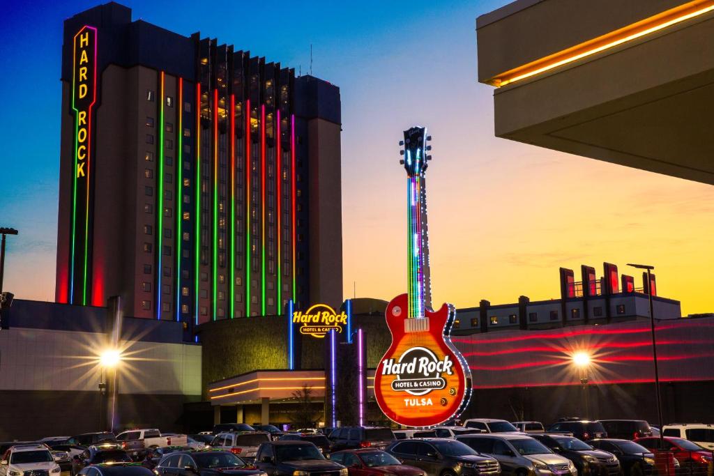 塔尔萨Hard Rock Hotel & Casino Tulsa的停车场的吉他标志,停车场有车辆停放