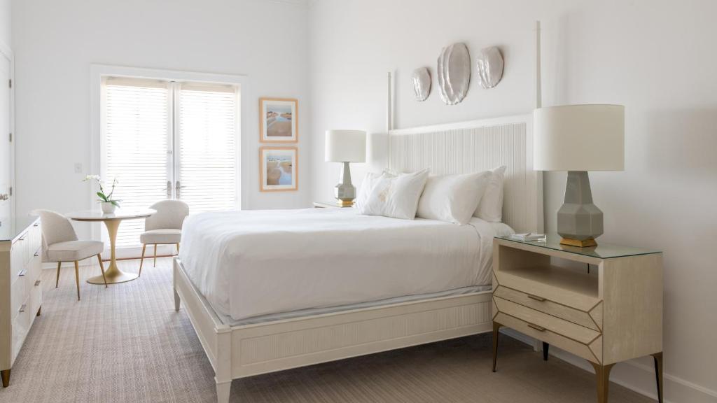 彭萨科拉Oyster Bay Boutique Hotel的白色的卧室配有白色的床和一张桌子