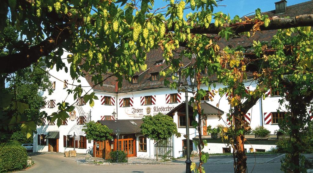 Irsee伊尔塞尔修道院啤酒厂酒店的一座白色的大建筑,有红色的窗户和树