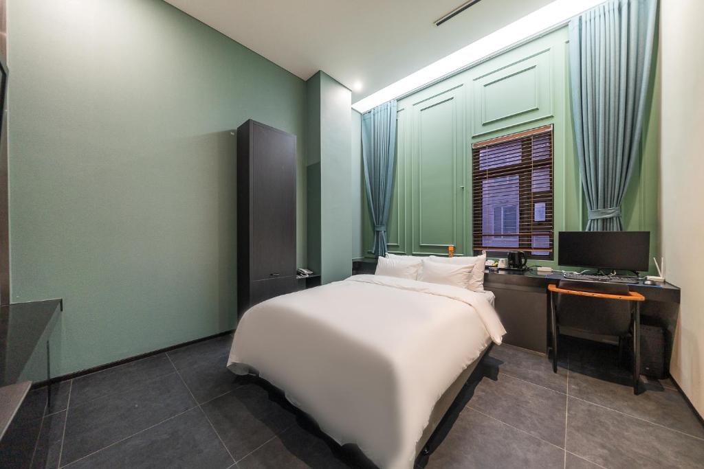 首尔Starhills Hotel的一间卧室配有一张床、一张书桌和一台电视