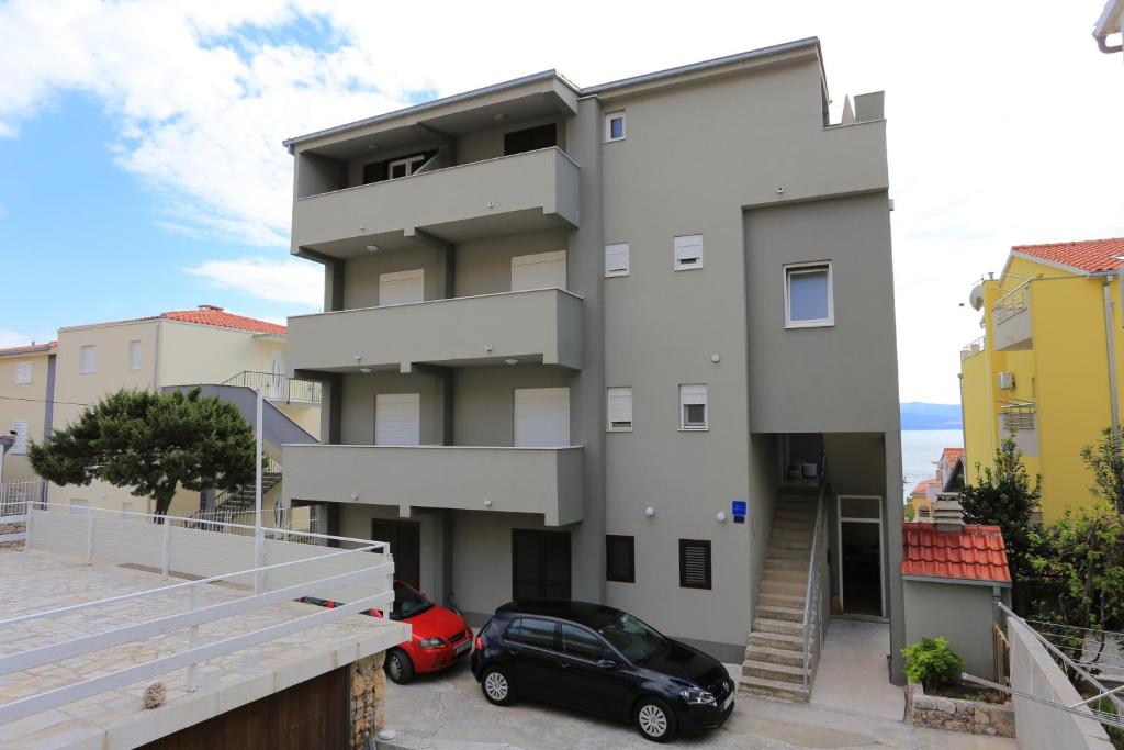 泰斯Apartments by the sea Nemira, Omis - 17039的前面有停车位的建筑