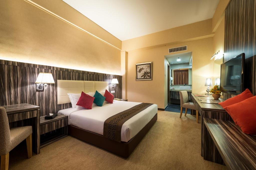 马六甲Hotel Sentral Melaka @ City Centre的酒店客房配有一张床、一张书桌和一台电视。