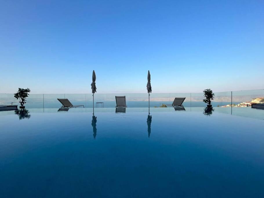 提比里亚Villa-SELAVI 3 unit complex with infinity pool的一个带椅子的游泳池,背景是大海