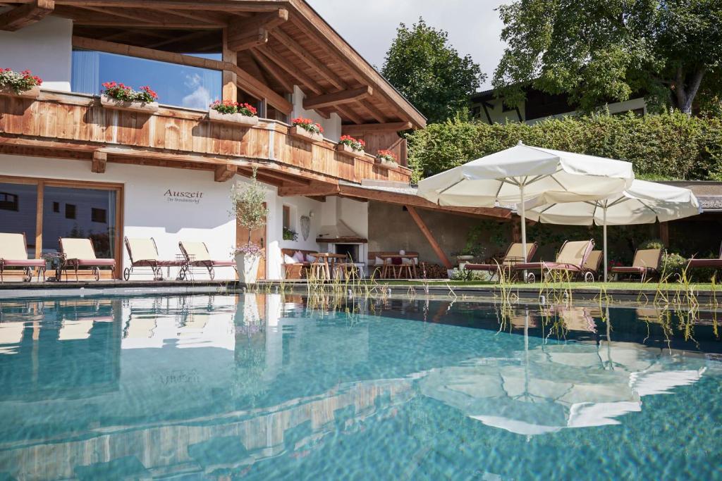 施坦斯Der Brandstetterhof - Adults only的一个带遮阳伞和椅子的游泳池以及一座房子