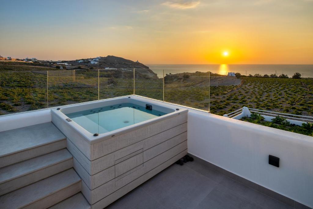 阿克罗蒂里La Ponta Villas & Suites的阳台上的热水浴池,享有日落美景