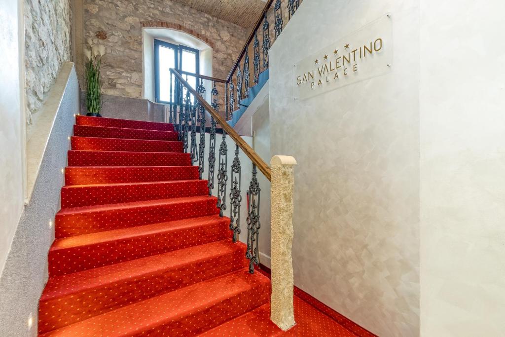 乌马格San Valentino Palace的铺有红地毯的楼梯和墙上的标志