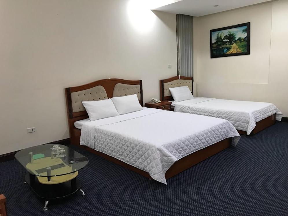 海防Thien Anh Hotel的酒店客房设有两张床和一张桌子。