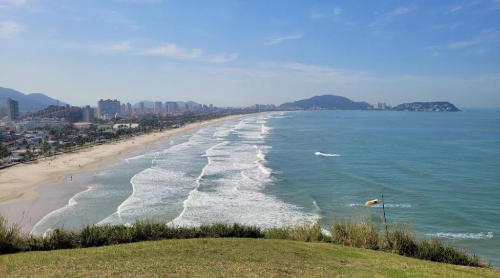 瓜鲁雅Apartamentos Enseada Guaruja的享有海滩美景,以城市为背景