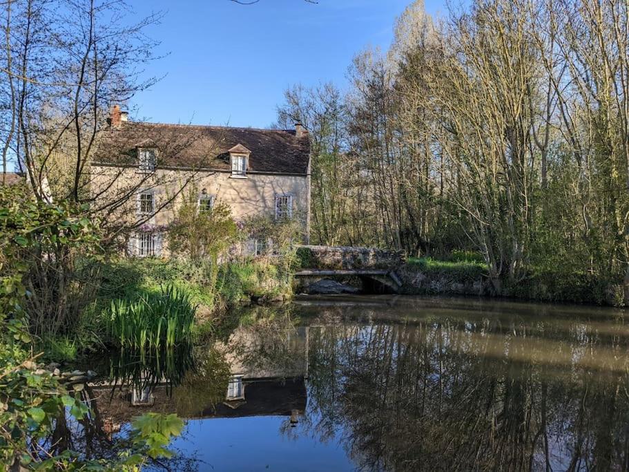 TrézanLe Moulin,19 bis rue de Beaudon, 45330 Augerville la riviere的一座古老的房子和一条有桥的河流