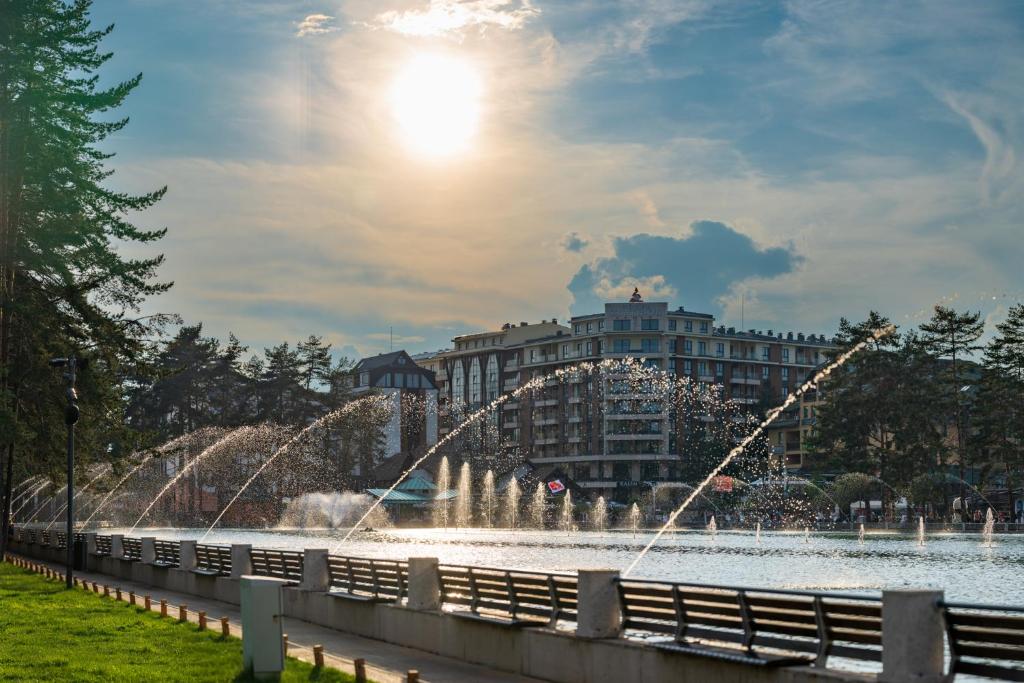 兹拉蒂博尔5 STARS - Luxury Premium WELLNESS RESORT Zlatibor的湖中的喷泉,有一座建筑的背景