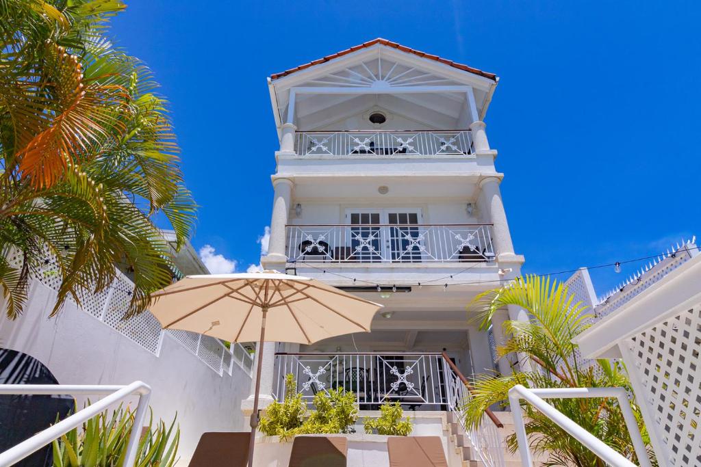 圣詹姆斯Bianca Bay 3 Bedroom West Coast Beach Front Villa的前面有一把伞的白色建筑
