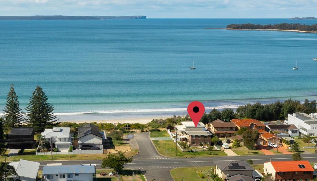 文森提亚Poseidons Hideaway by Experience Jervis Bay的享有海滩的空中景色,设有房屋和红色标志