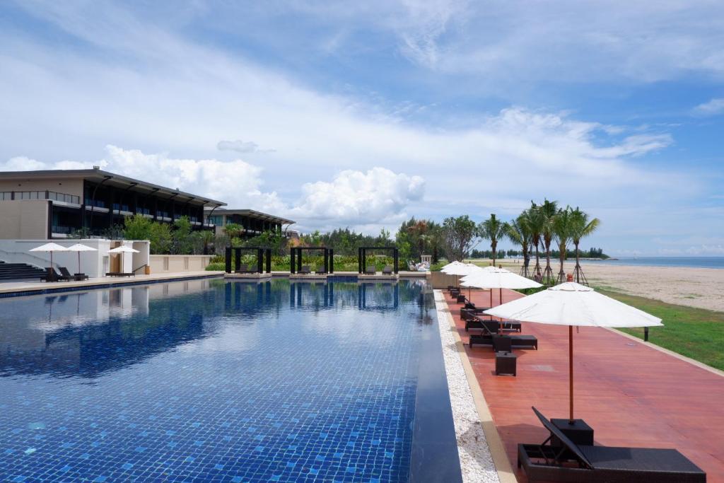 佛丕Sea Sand Sun Hua Hin Resort的一个带遮阳伞和海洋的游泳池