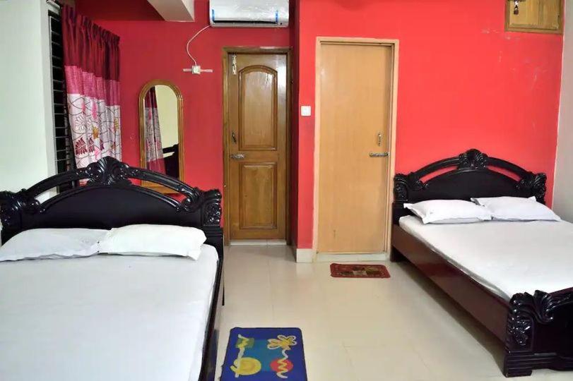 库克斯巴扎Sea Breeze Resort的红色墙壁的客房内的两张床