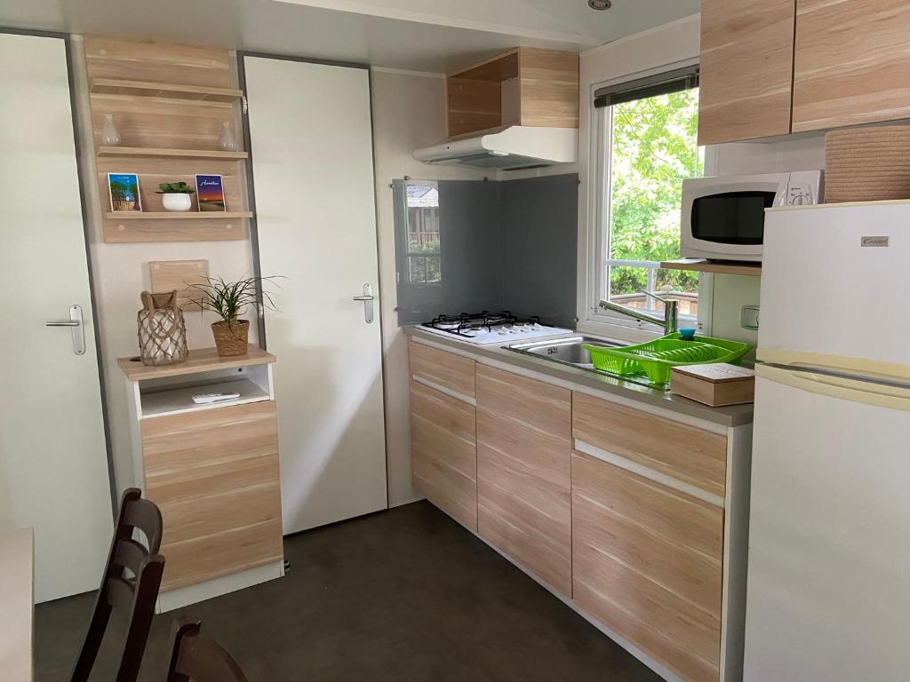 欧雷扬MOBIL HOME Climatisé G058的厨房配有木制橱柜和白色冰箱。