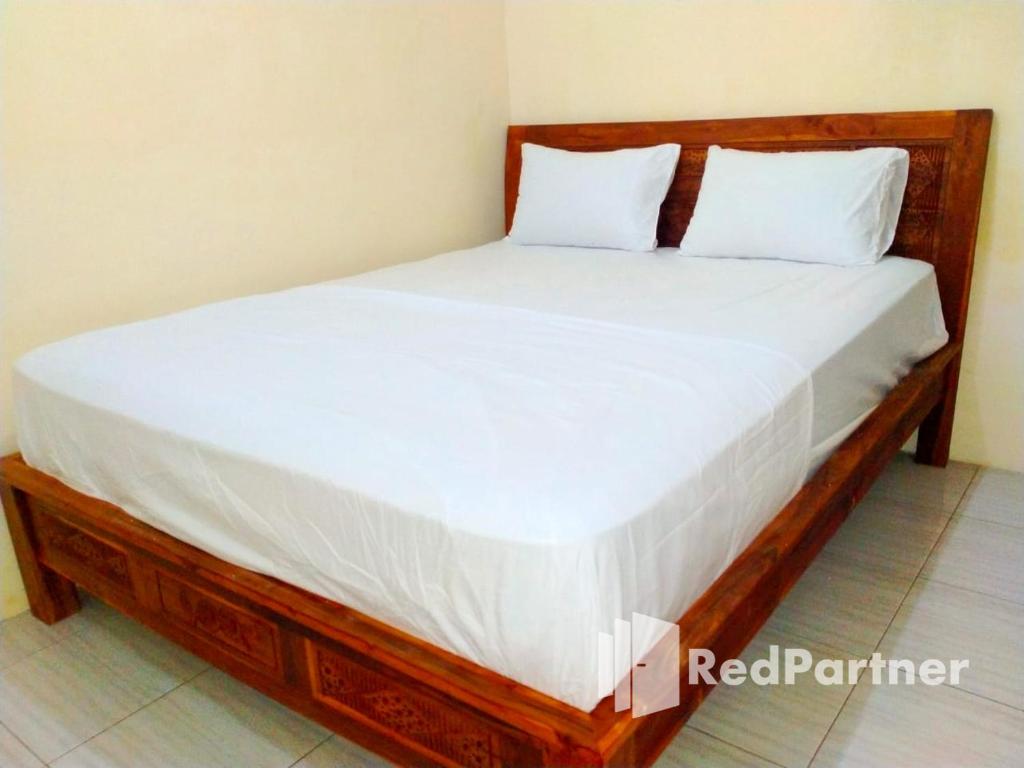 北加浪岸Navisha Guest House Syariah near Exit Tol Batang RedPartner的一张带白色床单和枕头的木床