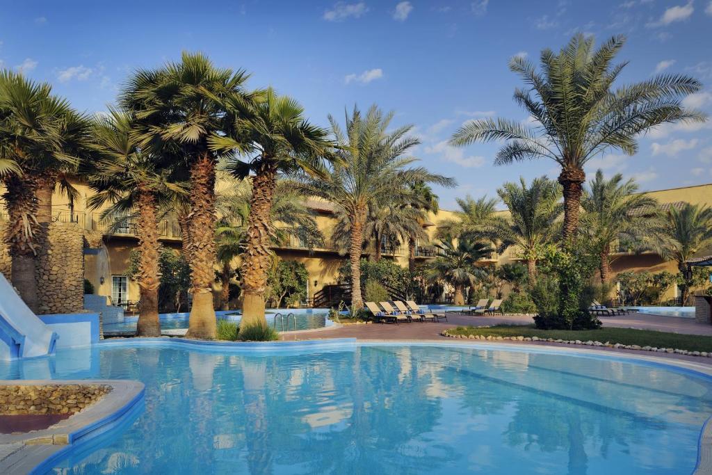 科威特Mövenpick Hotel Kuwait的度假村前方棕榈树游泳池
