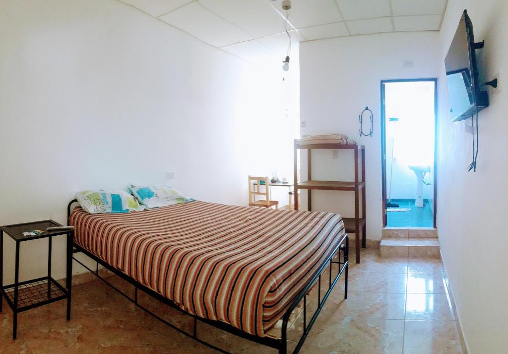 ChicoanaHostal Los Faroles Chicoana的一间卧室配有带条纹毯子的床