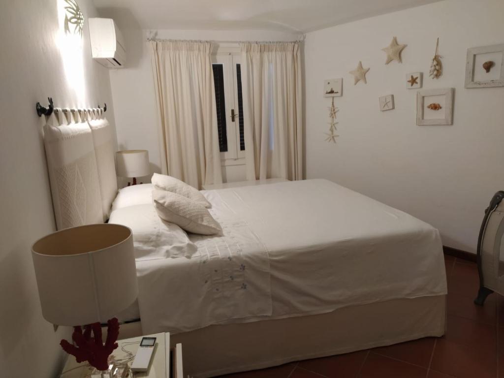 切尔沃港Appartamento Porto Cervo Dolce Sposa的卧室配有白色的床和带台灯的桌子