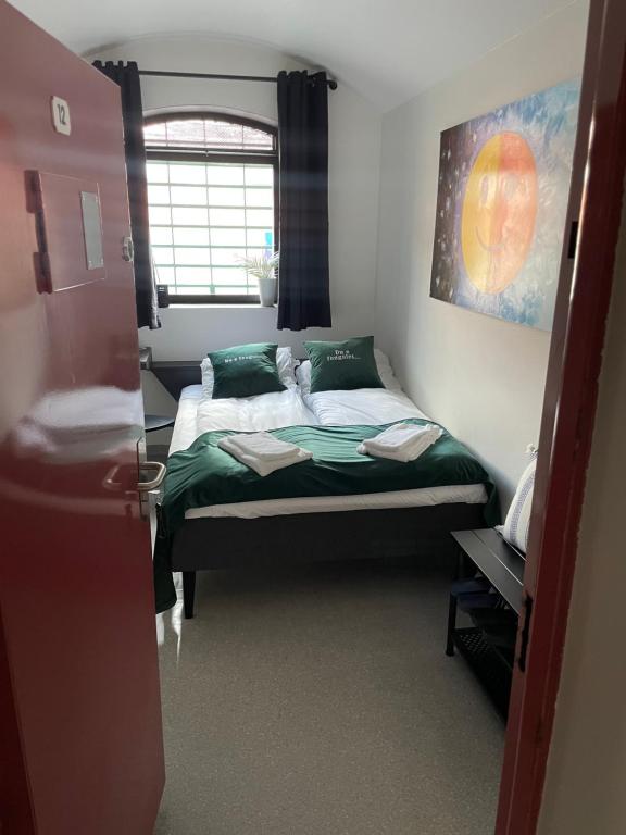 阿伦达尔Fengselshotellet AS的一间卧室配有一张带绿色床单的床和一扇窗户。