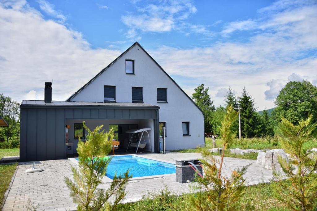 奥古林Family friendly house with a swimming pool Ostarije, Gorski kotar - 18952的一座白色的房子,前面设有一个游泳池