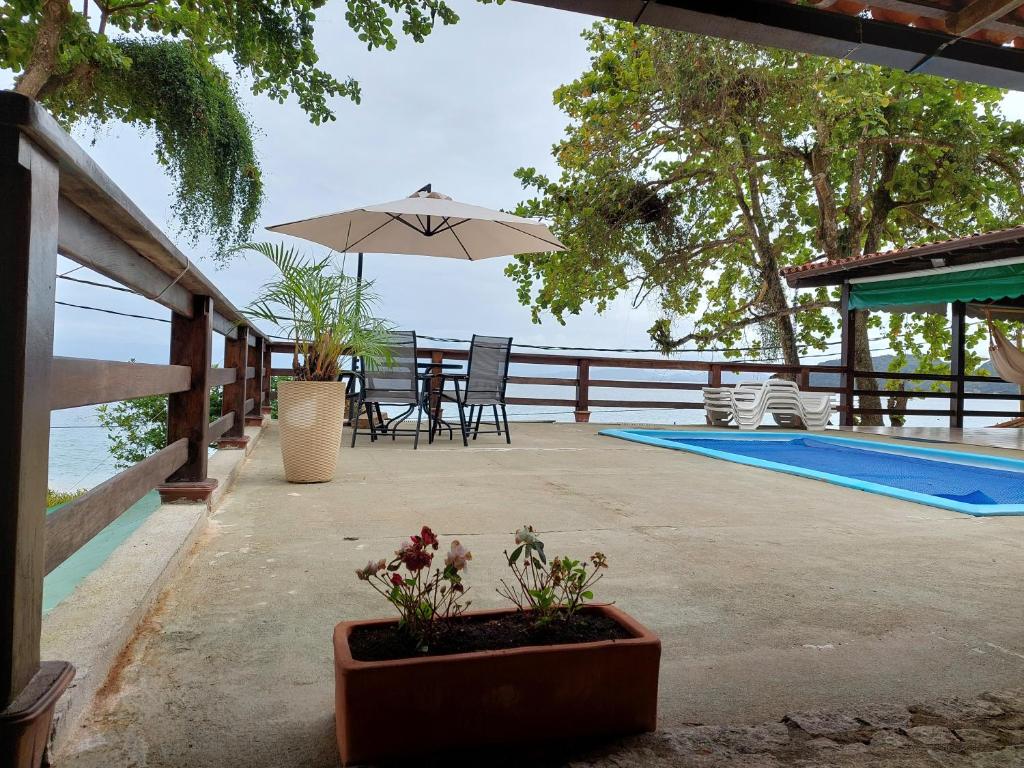 阿拉夏奇巴海滩Espaço Villa Ará的一个带桌子和遮阳伞的庭院,毗邻一个游泳池