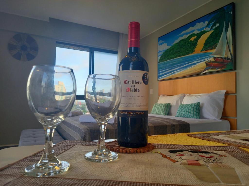 纳塔尔Ilusion Flats Aconchego de Ponta Negra的桌子上放有一瓶葡萄酒和两杯酒