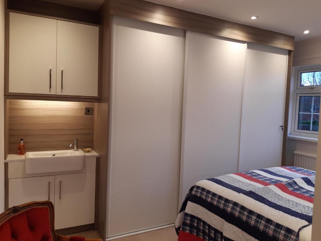 拉尔Smitten House 4 Bedroom RHYL的卧室配有白色橱柜、水槽和床。