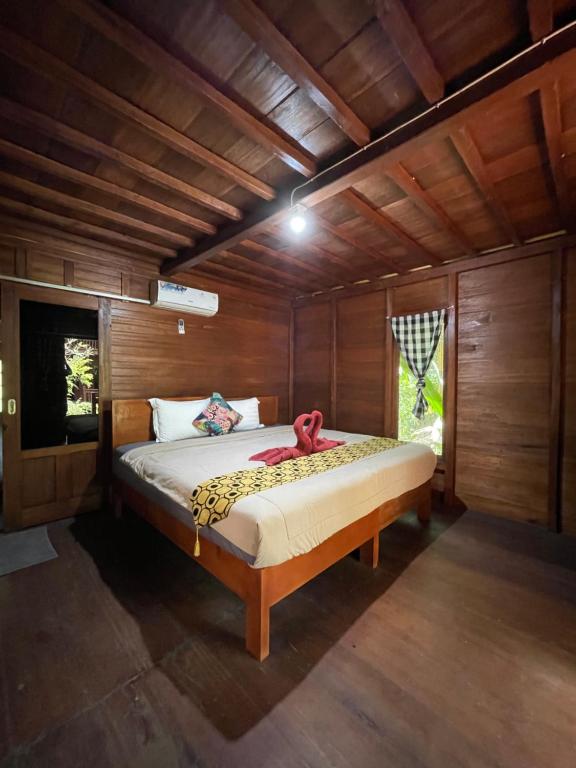 Kubutambahan布连民宿的木制客房内的一间卧室,配有一张床